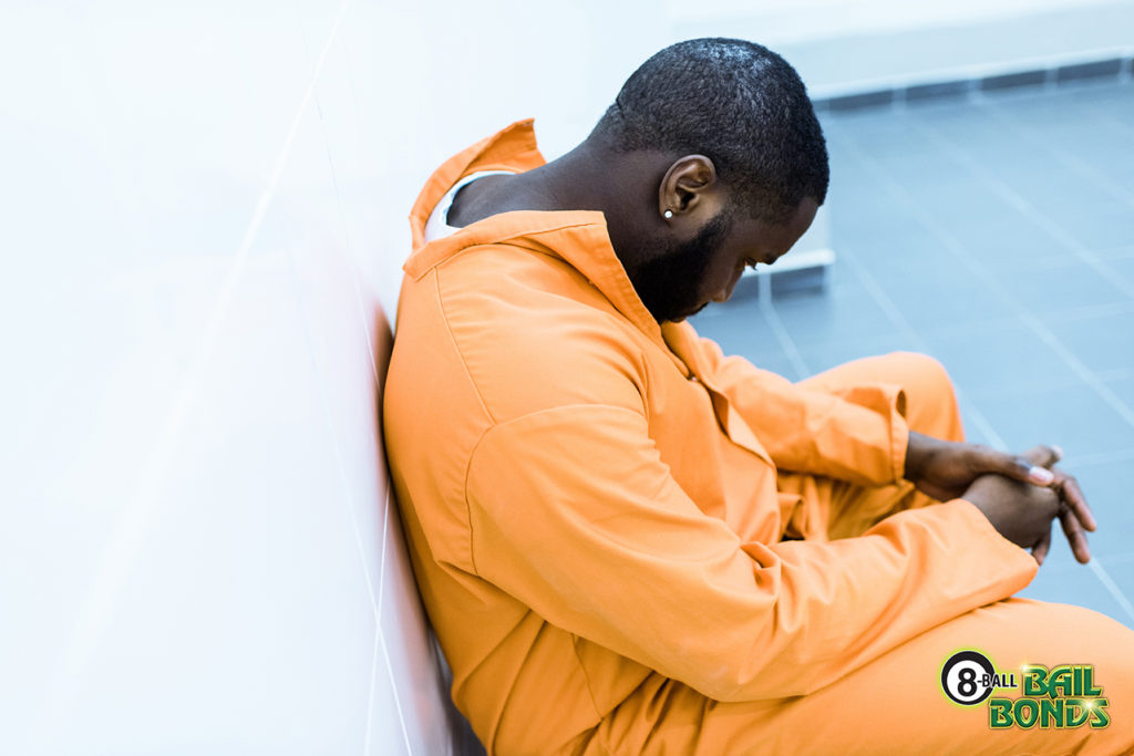 Your rights as an inmate: a man in an orange jumpsuit sitting with his head down